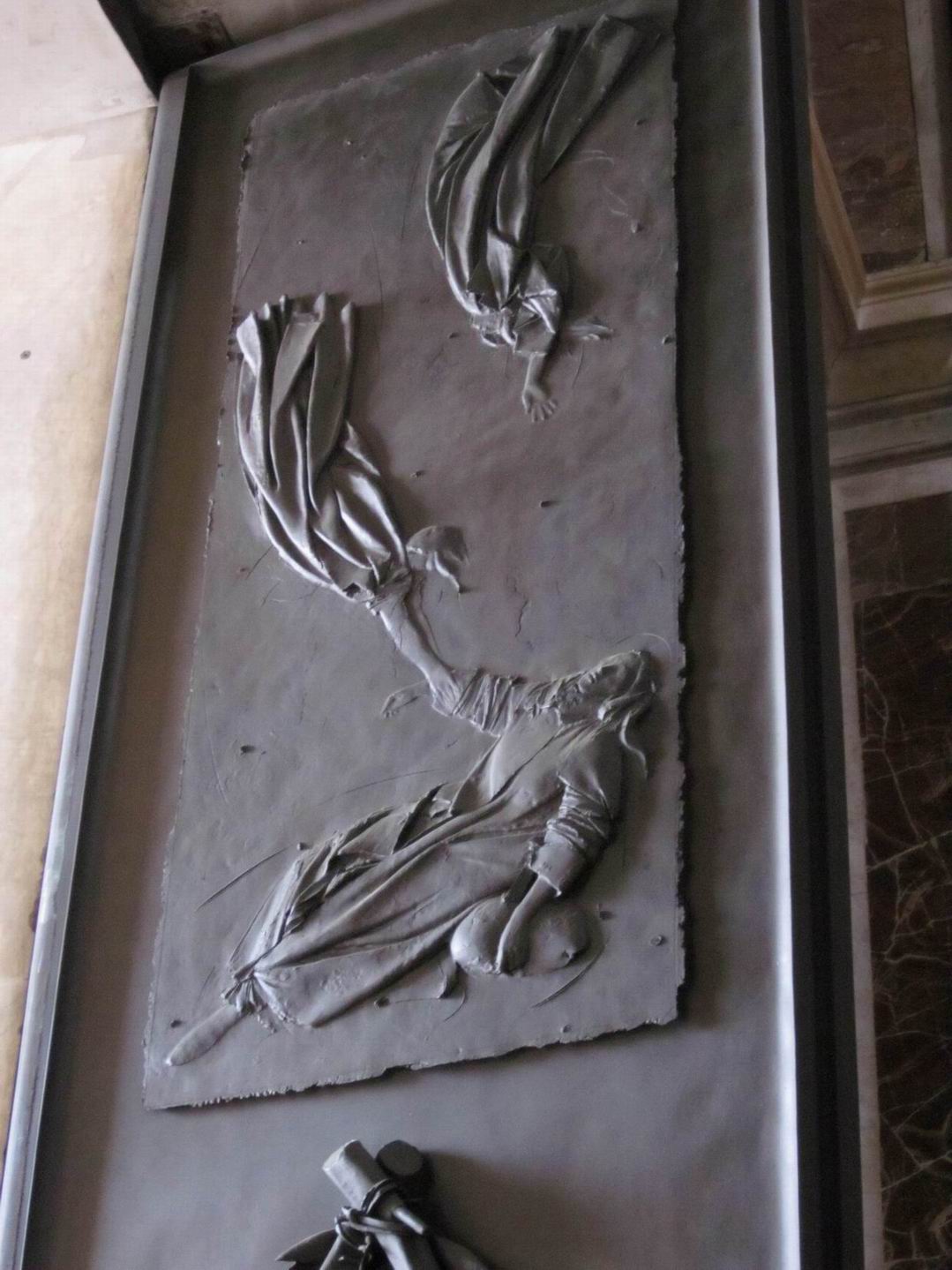 A imagem exibe um segmento da "Porta da Morte" da Basílica de São Pedro, apresentando figuras em relevo que expressam movimento e dramatismo, esculpidas com riqueza de detalhes.