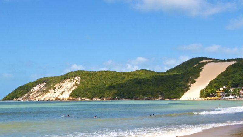 Vista da Praia de Ponta Negra em Natal - RN, com destaque para o icônico Morro do Careca e suas águas tranquilas.